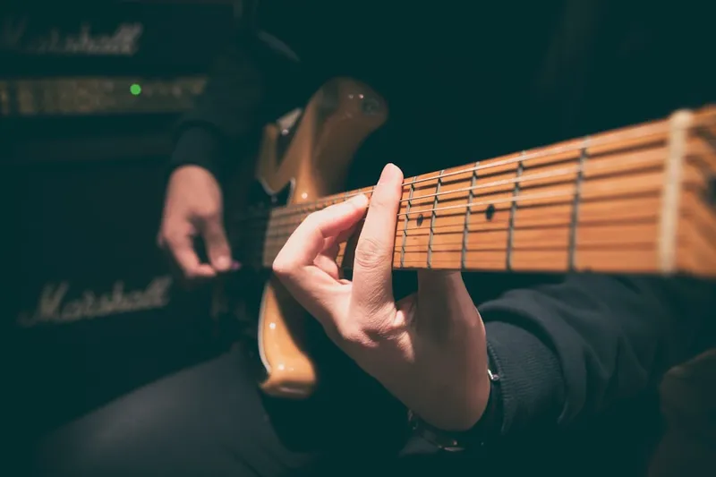person wearing black shirt paying guitar in closeup photography