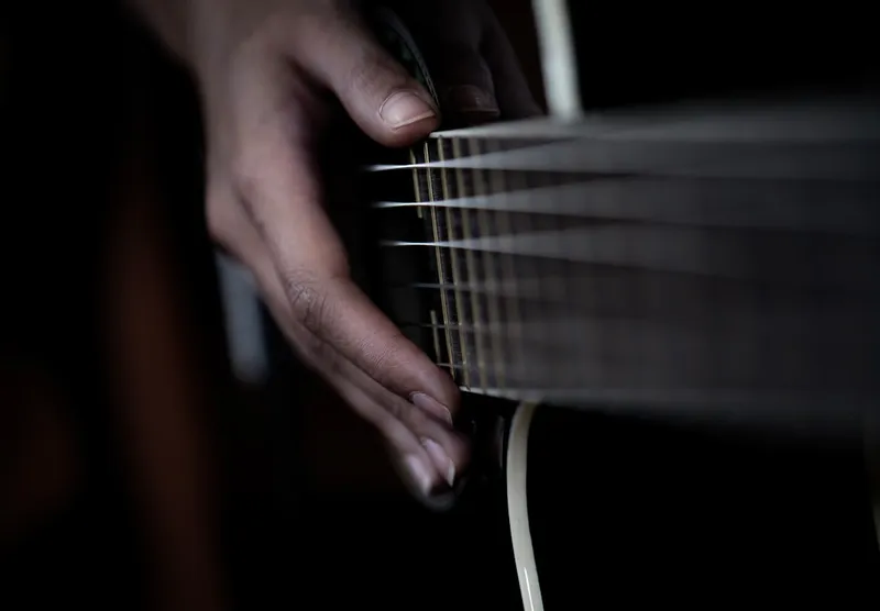 Hand strumming strings of an acoustic guitar